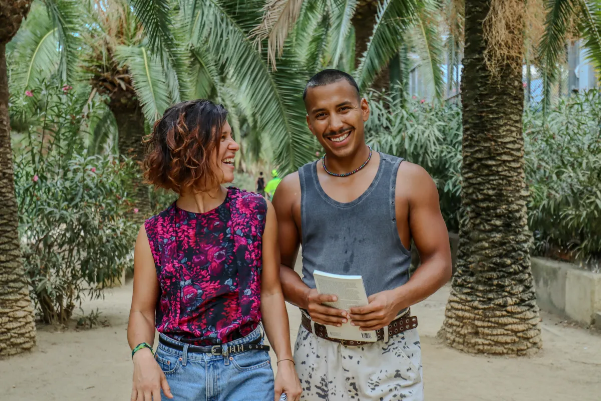 Emi and Nano smiling at the camera between palm trees
